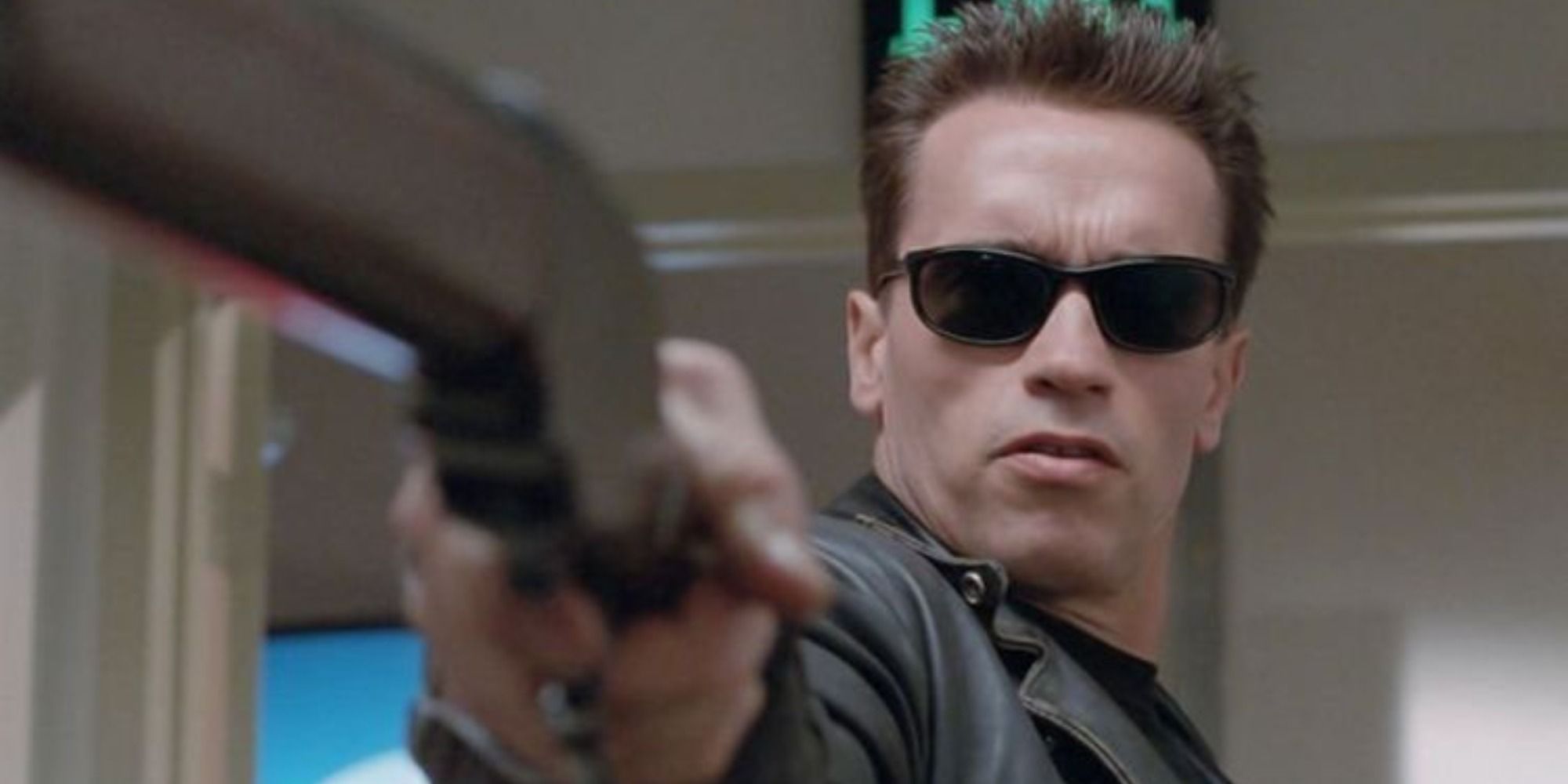 Arnold Schwarzenegger dans le rôle de Terminator portant des lunettes de soleil et un pistolet pointé