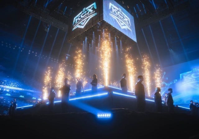 K-Corp vs The World 2023, montrant plusieurs joueurs sur scène avec des lumières bleues soulignant l'arène